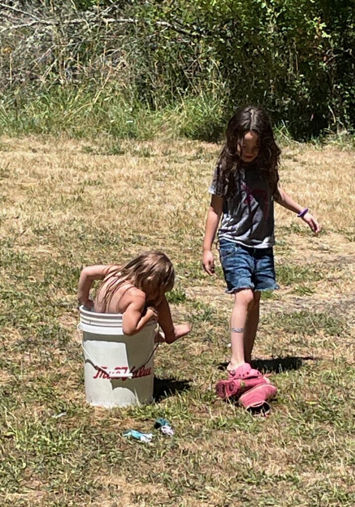 Girls playing with a bucket full of water.